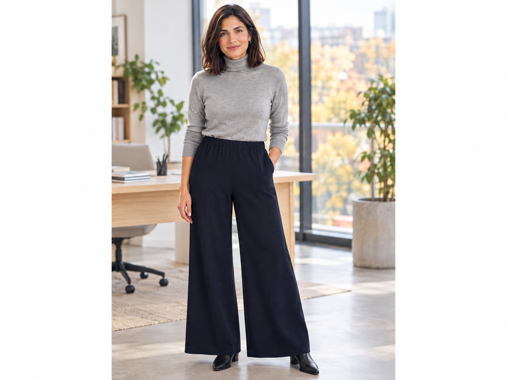 Donna sui 45 anni con pantaloni palazzo neri Dorabella e dolcevita grigio in un ufficio luminoso d'autunno