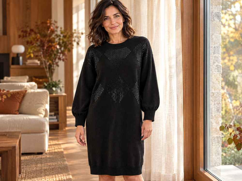 Donna sui 45 anni con abito in maglia nero Dorabella in un interno caldo, guida agli abiti per donne curvy