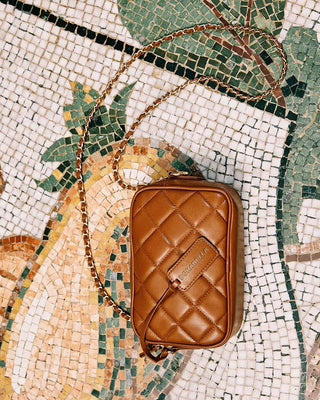 Elegant brown quilted bag with gold chain on artistic mosaic background, perfect for Autumn Winter 2024 fashion.