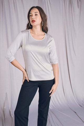 Maglia bi-materiale grigio-perla con applicazioni strass, abbinata a pantaloni neri per un look elegante e luminoso.