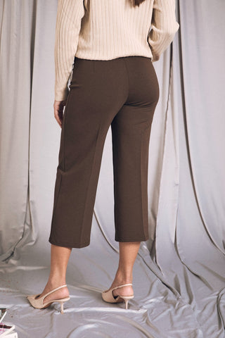 Back view of comfy cropped pants with elastic waist in dark brown, styled with a cozy sweater and heels.