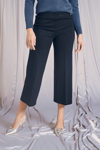 Comfy cropped blue pants with elastic waist, featuring a culotte cut, styled with a cozy sweater and chic shoes.