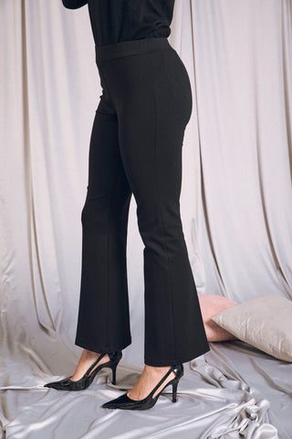 Pantalone flare nero con vita elastica, indossato da donna elegante, perfetto per look casual o chic con tacchi.